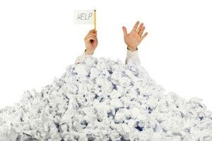 Person under crumpled pile of papers with hand holding a help sign / isolated on white