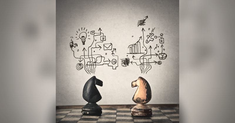 Two chess knights facing each other on a board, with hand-drawn arrows, charts and a light bulb sketched above them